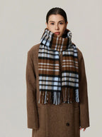 Woman wearing a brown plaid scarf with blue and black accents, draped over a brown coat.