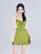 Woman wearing a green ruffled mini dress with a white sheer cardigan