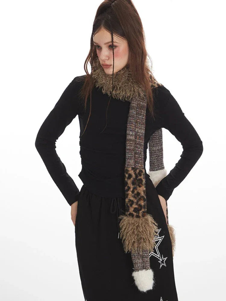 Close-up of a model wearing a black long-sleeve top and a black maxi skirt with a drawstring waist and white star graphics, with a multi-patterned scarf draped around her neck.