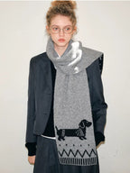 Woman in a gray suit and a gray knit scarf with a dachshund pattern.