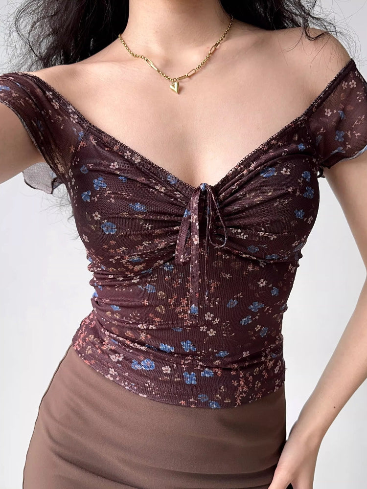 Model wearing a brown floral print mesh top with short flutter sleeves and a sweetheart neckline
