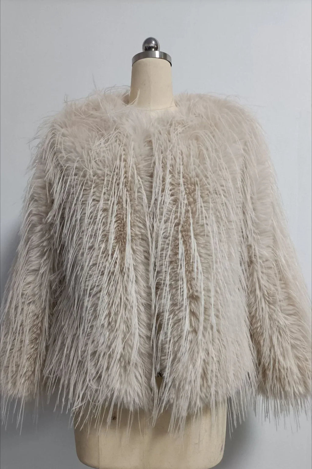 Light beige faux fur jacket with a shaggy, fringed texture displayed on a mannequin.