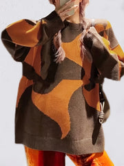 Close-up of a woman wearing a brown and orange abstract patterned oversized sweater with pink braided hair.