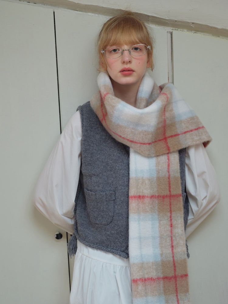 Close-up of a woman wearing a plaid scarf with a white shirt and grey vest.