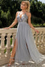 Woman wearing a light grey sequined and tulle evening gown with a high slit.