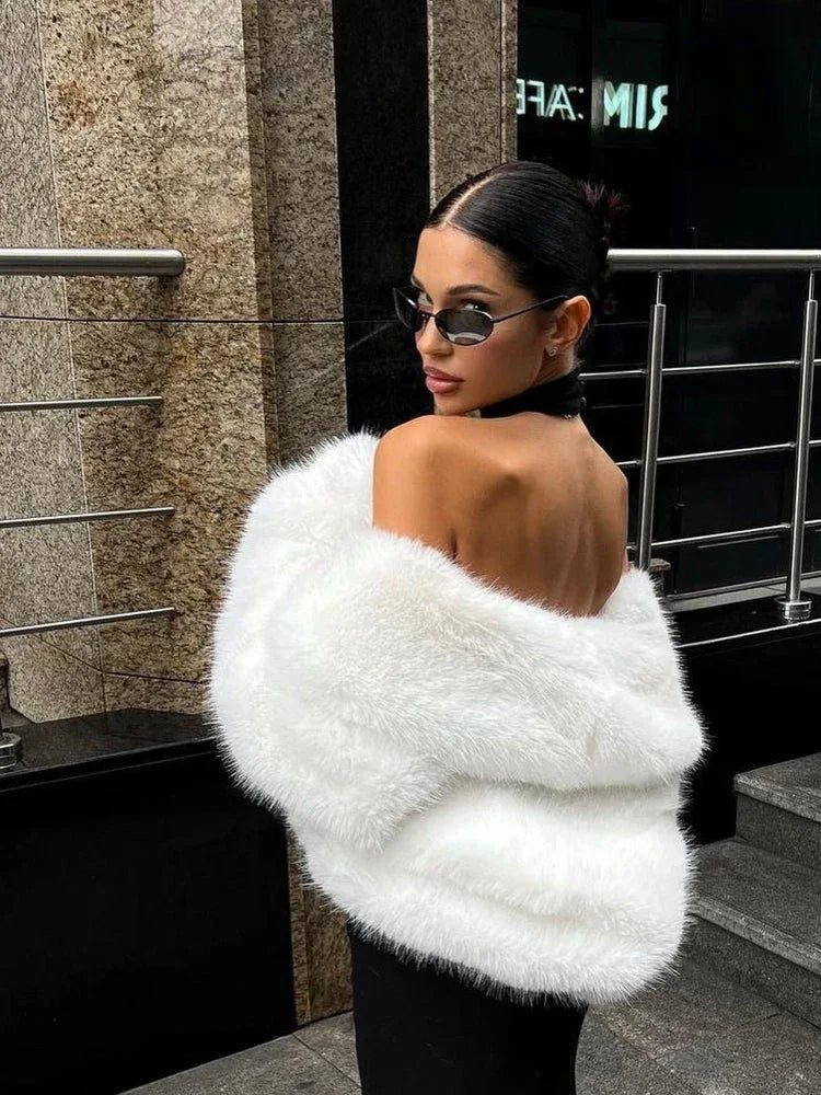 woman looking over her shoulder in a black dress and white faux fur jacket