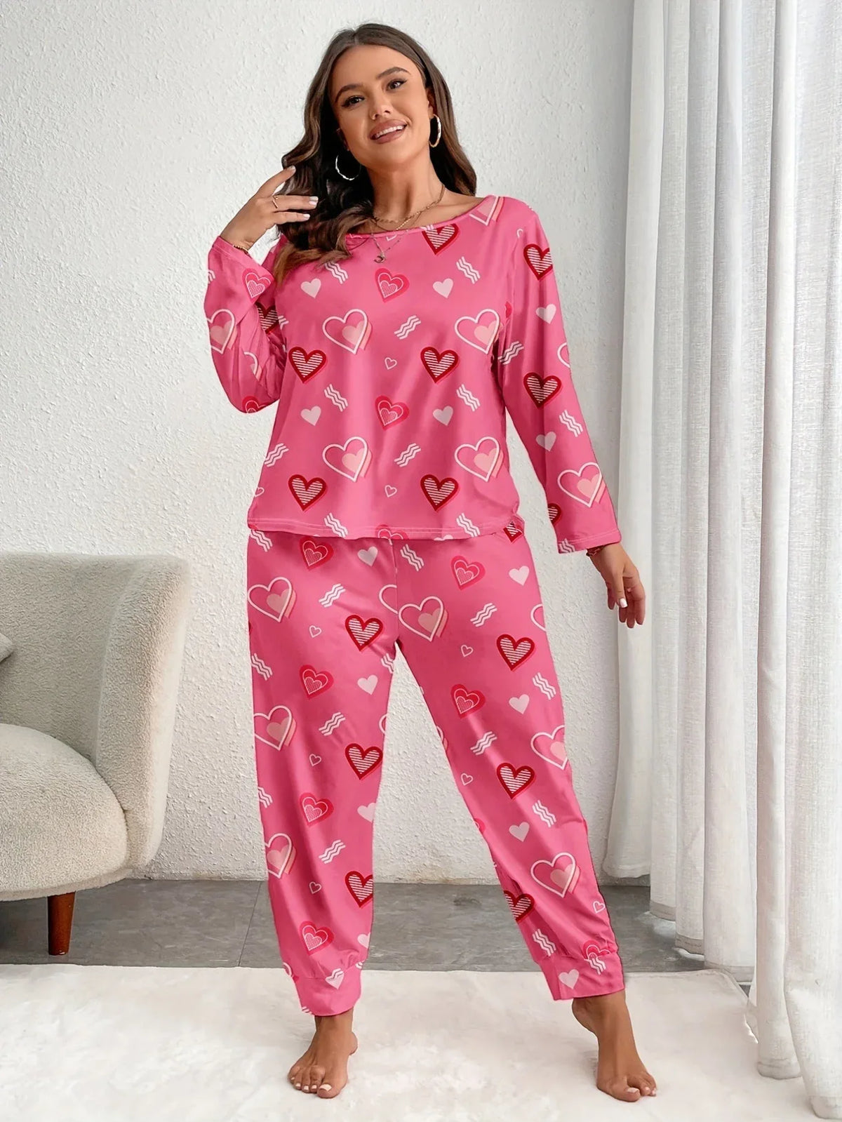 Woman wearing pink heart-print pajamas, standing and smiling. Main image