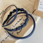 Two denim headbands, one padded and one with knotted fabric and clips, on a cloth.