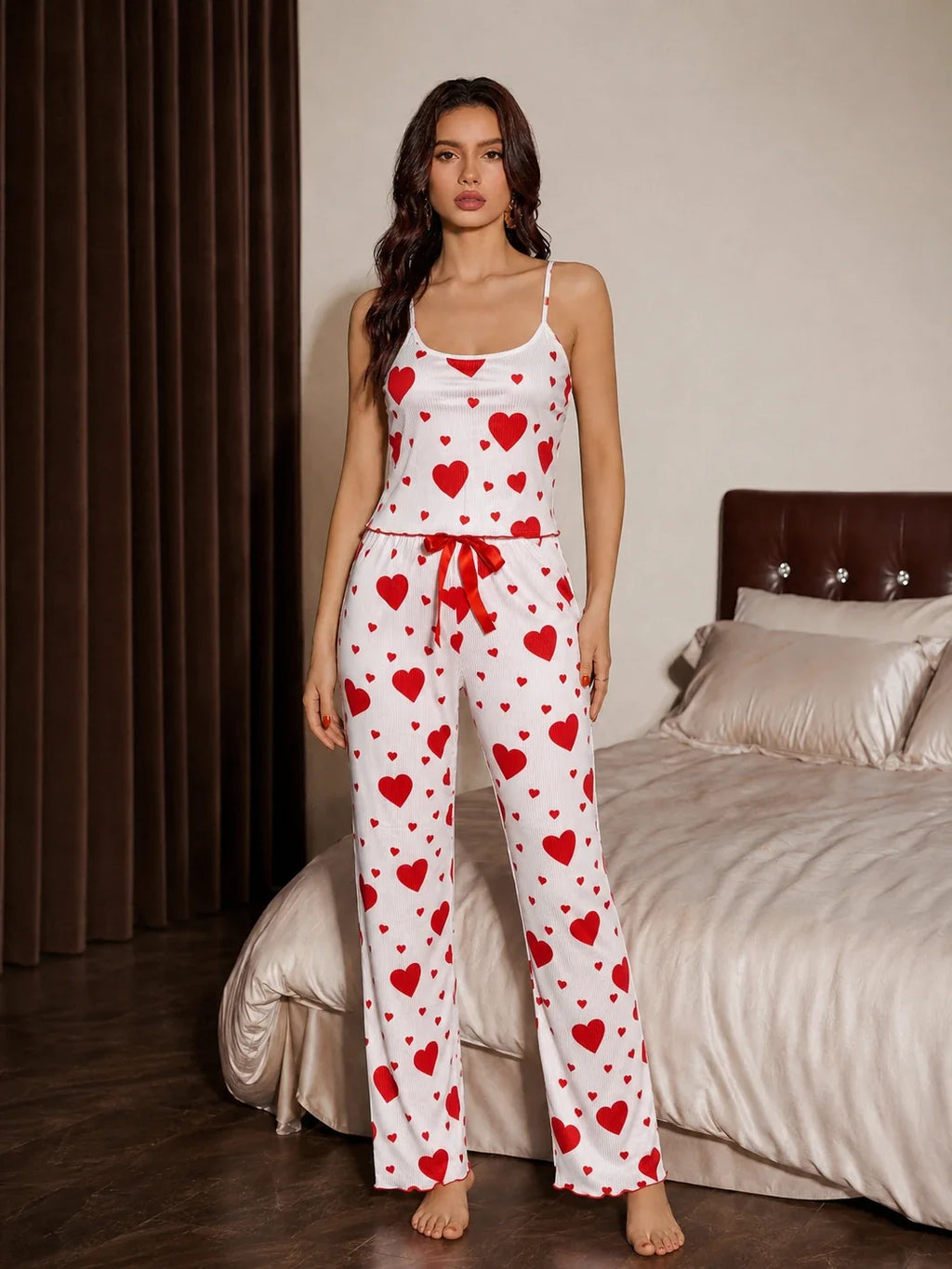 Front view of a woman wearing a white and red heart print pajama set with spaghetti straps and a drawstring waist.
