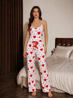 Front view of a woman wearing a white and red heart print pajama set with spaghetti straps and a drawstring waist.