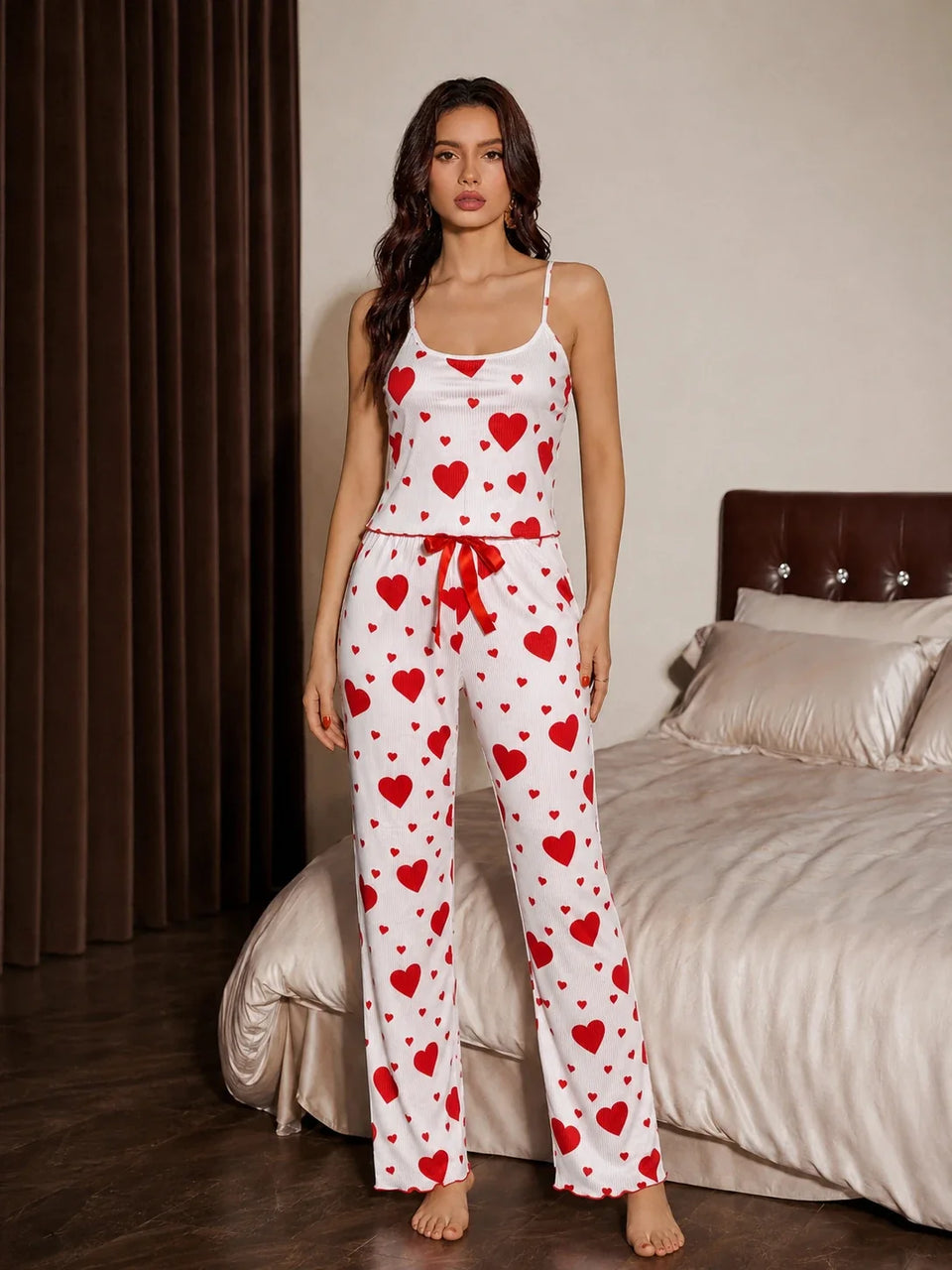 Front view of a woman wearing a white and red heart print pajama set with spaghetti straps and a drawstring waist. Main image