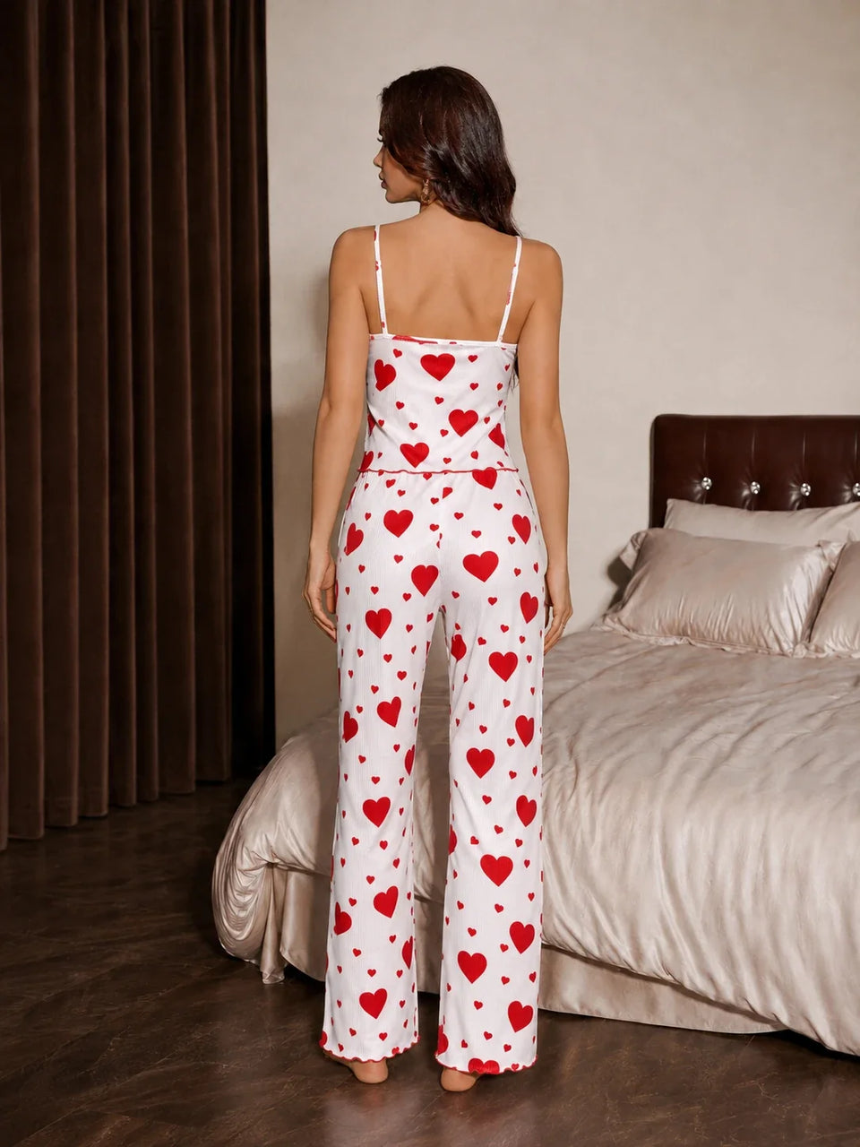 Back view of a woman wearing a white and red heart print pajama set with spaghetti straps and a drawstring waist. Secondary image