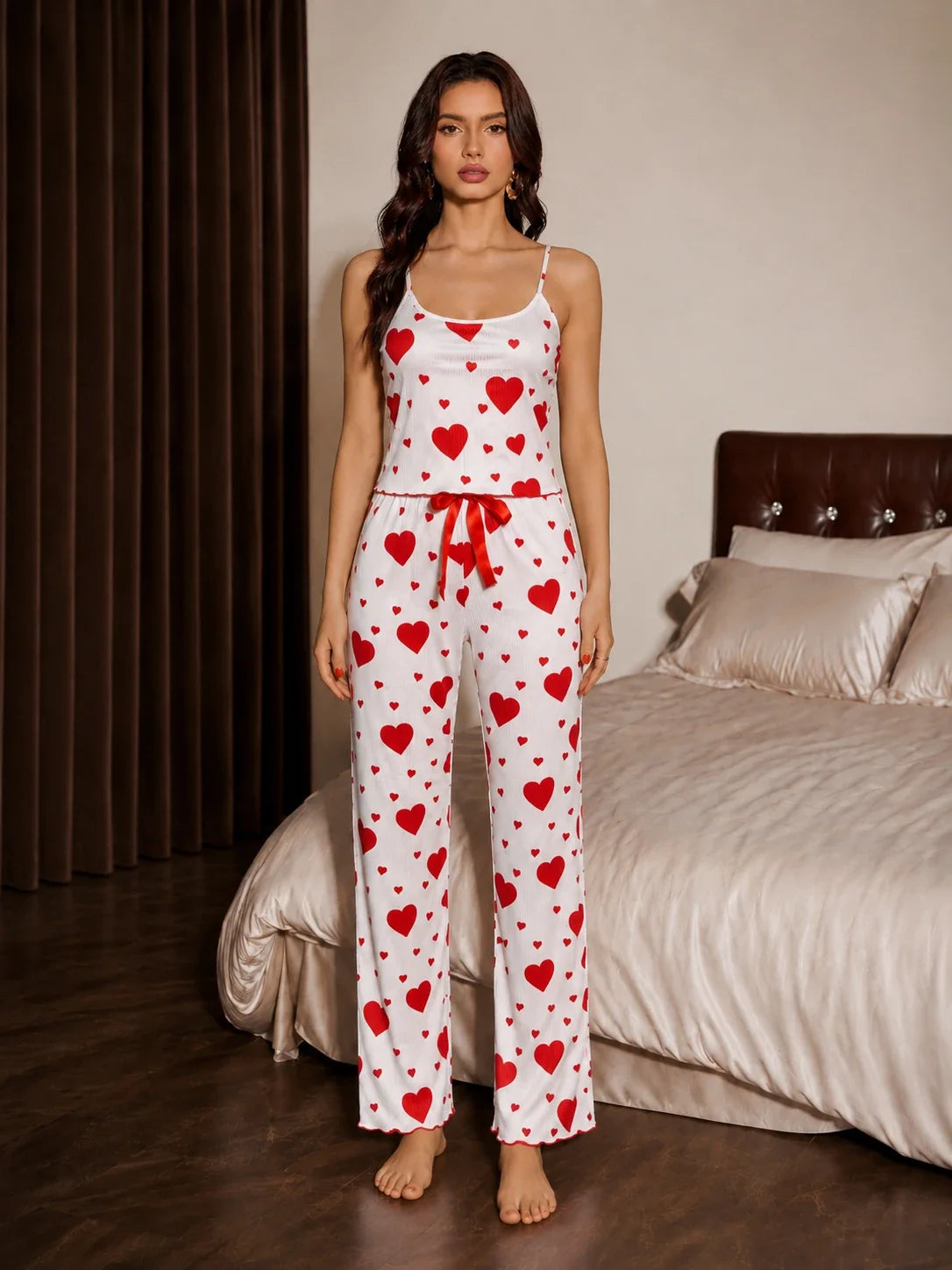 Full body shot of a woman in a heart patterned cami and pant pajama set.