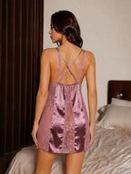 Back view of a woman wearing a purple satin and lace chemise with criss-cross straps
