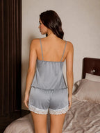 Back view of a woman wearing a grey satin and lace pajama set, showing the spaghetti straps and shorts with lace trim
