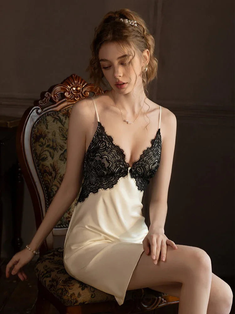 Woman wearing a cream-colored satin chemise with black lace trim, sitting on an ornate chair. Main image
