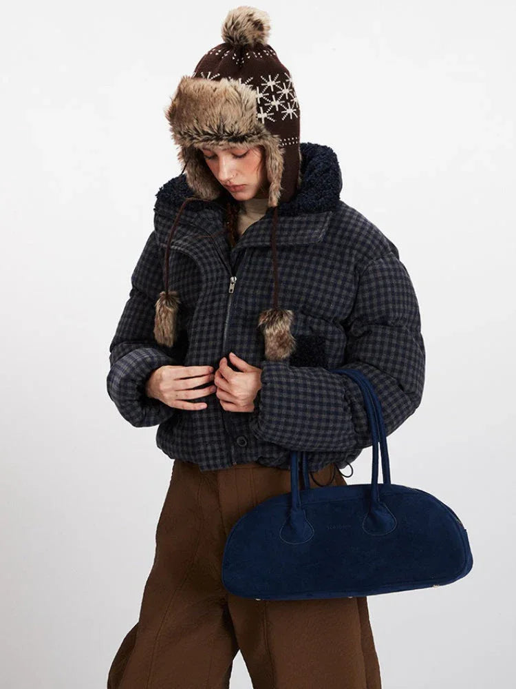 Close-up of a woman wearing a plaid puffer jacket and trapper hat, adjusting the zipper.