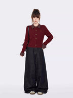 Woman posing in a stylish burgundy cable knit cardigan and dark denim.
