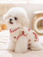 White poodle wearing a cream-colored dog vest with cartoon bears and red gingham trim