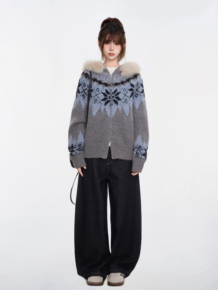 Full-body shot of a woman in a grey and blue Fair Isle knit zip-up cardigan with a faux fur trim hood and black wide-leg jeans