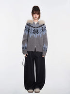 Full-body shot of a woman in a grey and blue Fair Isle knit zip-up cardigan with a faux fur trim hood and black wide-leg jeans