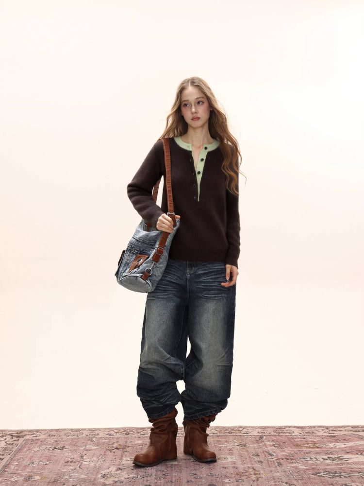 Woman wearing a brown knit henley sweater with a light green collar, dark wash wide-leg jeans, brown boots, and a denim shoulder bag.