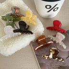 Various acetate claw hair clips arranged on a textured surface, with a coffee cup in the background