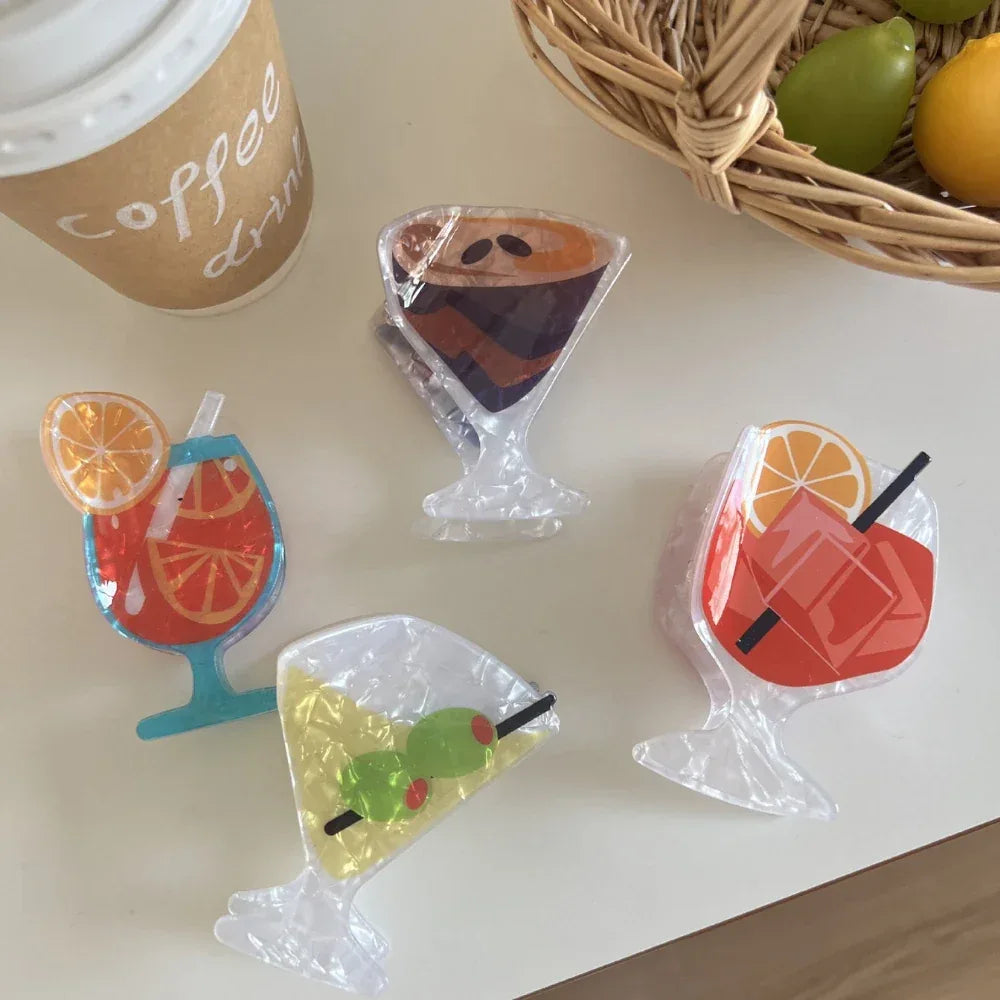 top-down view of four acrylic cocktail hair clips alongside a coffee cup and fruit basket