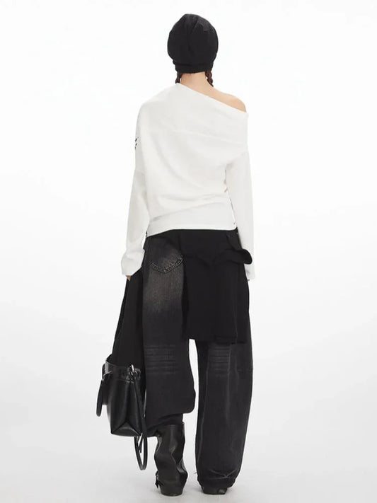 Back view of a model wearing a white long-sleeved off-the-shoulder top with distressed graphic print and black wide-leg jeans.