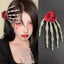 Woman with dark hair styled with a skeleton hand hair clip featuring a red flower