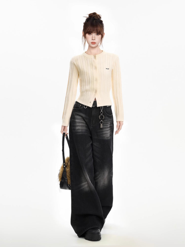 Full body shot of a woman wearing a cream cable knit cropped cardigan with black wide-leg jeans, a black belt, and a black fur bag