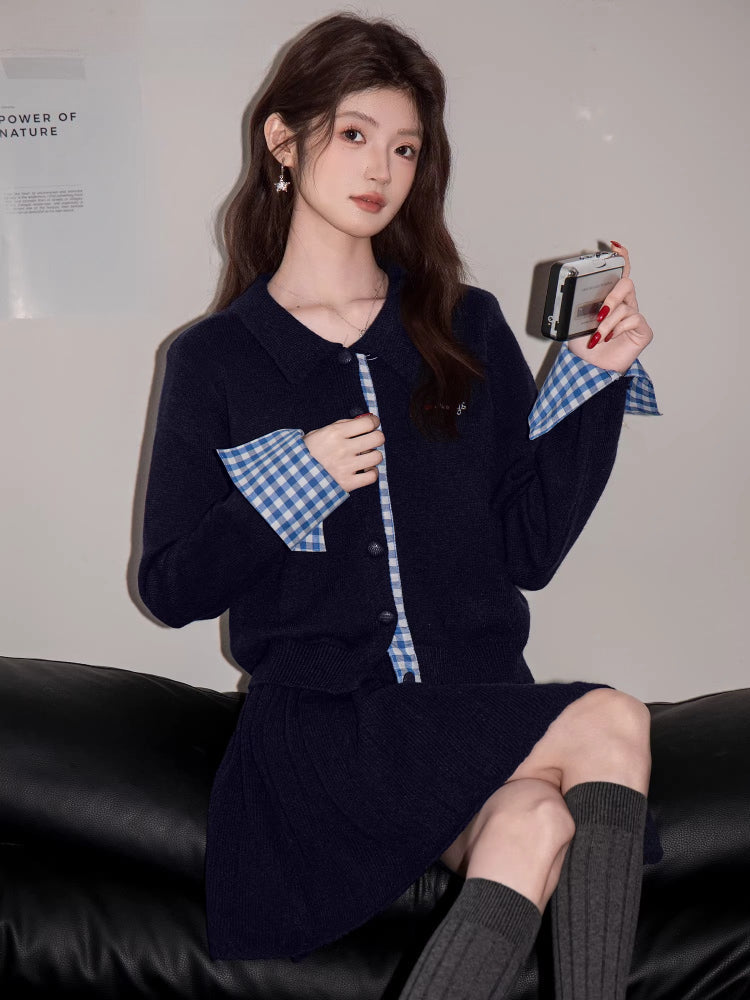 Woman in a navy blue knit outfit with gingham trim, holding a small silver device.