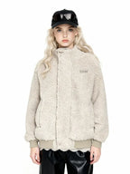 Front view of a woman wearing a cream-colored sherpa fleece bomber jacket, black faux leather pants, and a black baseball cap with sunglasses.