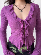 Detailed view of the neckline and tie-front closure of a purple floral lace top.