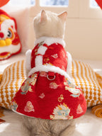 The back view of a cat in a red, festive dress with dragon patterns and white faux fur trim. The dress has a D-ring for leash attachment.