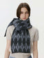 Woman wearing a cream cable-knit sweater and a grey and black argyle scarf