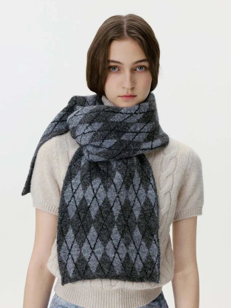Woman wearing a cream cable-knit sweater and a grey and black argyle scarf