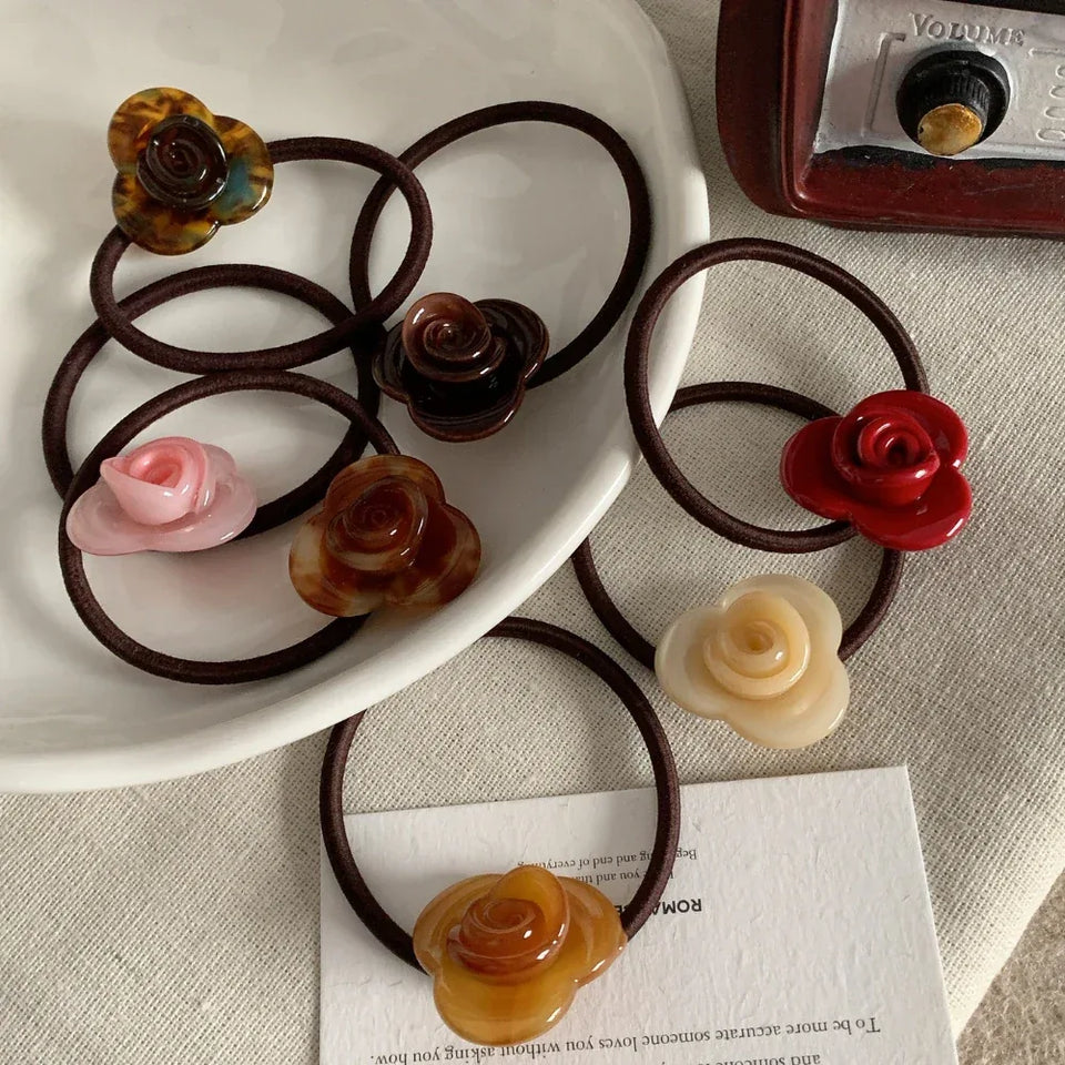A collection of rose-shaped hair ties in various colors arranged on a white plate. Secondary image