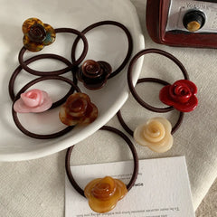A collection of rose-shaped hair ties in various colors arranged on a white plate.