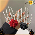 Two skeleton hand hair clips, one with a red flower and one with a black flower