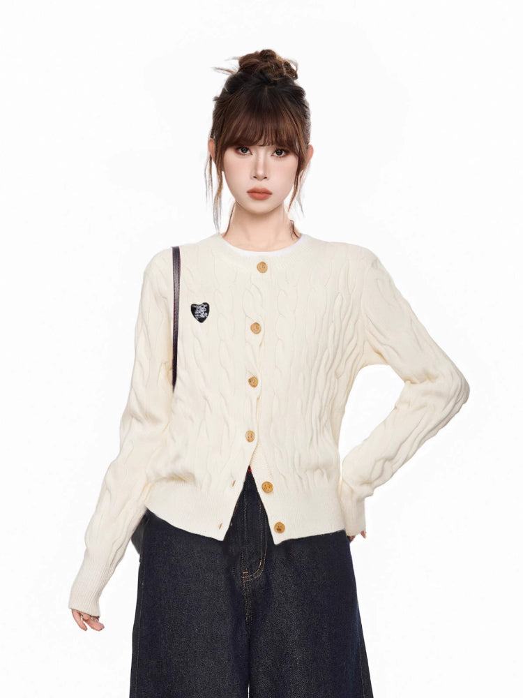 Close-up of the cream cable knit cardigan with a heart patch