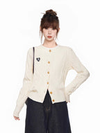 Close-up of the cream cable knit cardigan with a heart patch