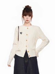 Close-up of the cream cable knit cardigan with a heart patch