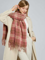 Woman adjusting her pink and tan plaid scarf, smiling slightly.