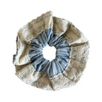 A close-up of a scrunchie with blue and white stripes and a lace trim.