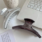Silver and dark grey metallic claw clips positioned near a laptop keyboard