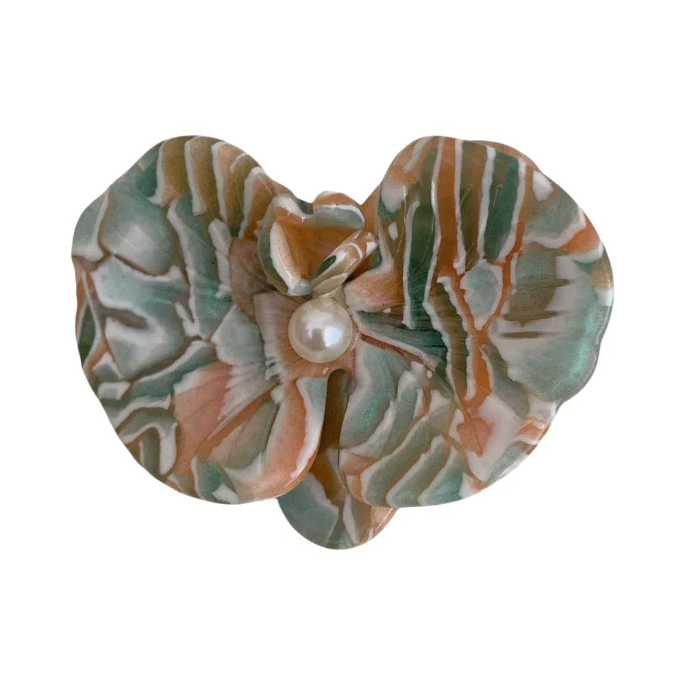 Close-up of a marbled floral hair clip with a pearl center.