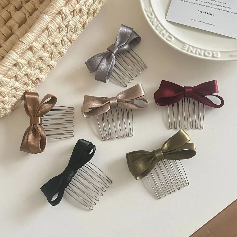 A spread of satin bow hair combs in different colors, displayed on a white tabletop.