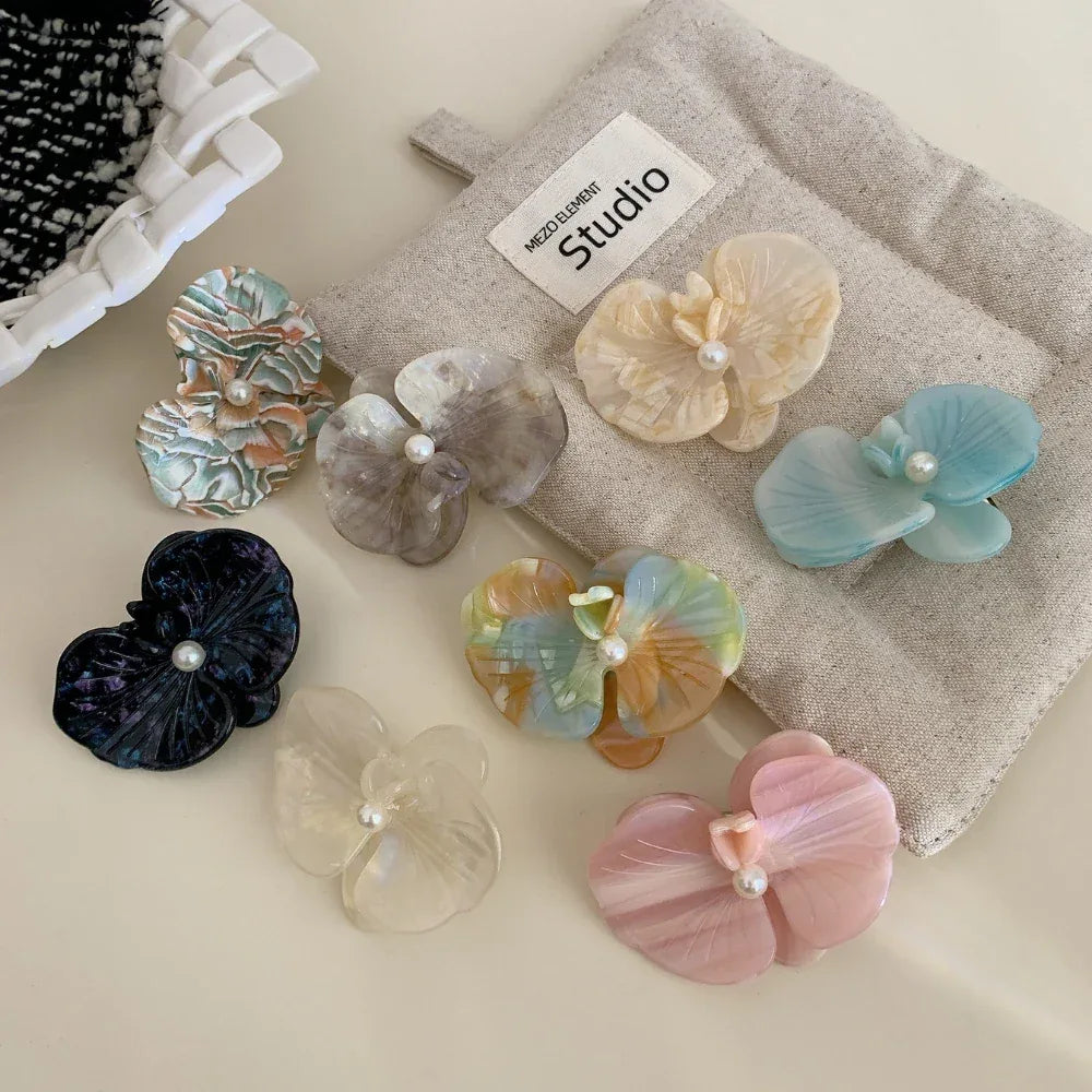 An assortment of translucent floral hair clips with pearl embellishments.