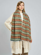 Woman wearing a cream coat and a multi-colored striped scarf with cream fringe